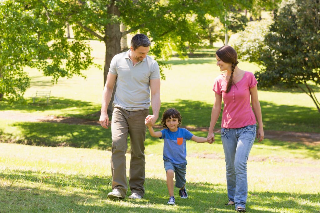 A young family walking while holding hands in a park