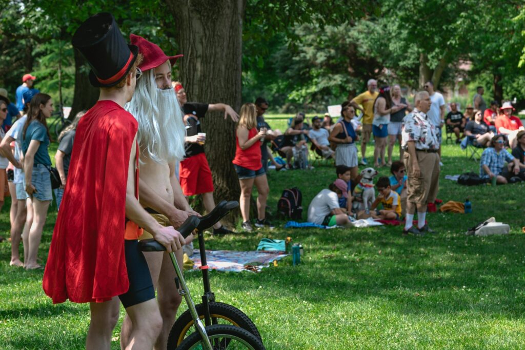 Visitors and performers standing and sitting on a green space in the concept of 'best parks and green spaces in Chelsea'.